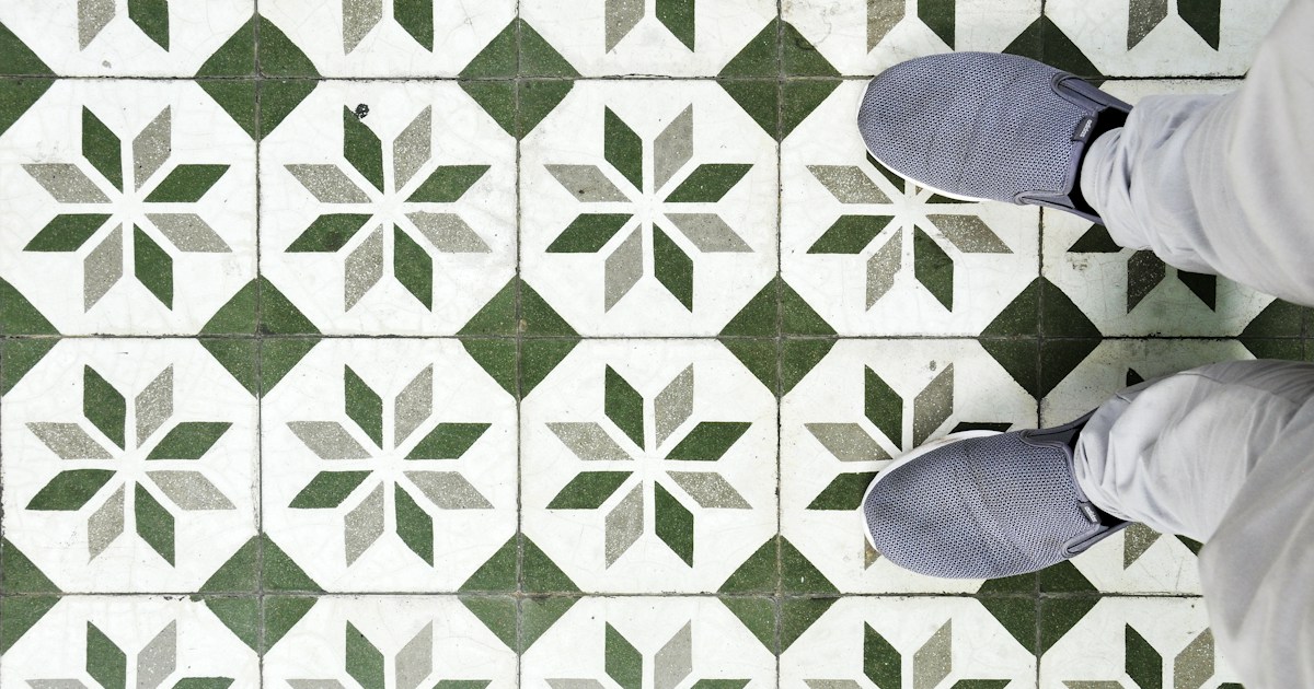 Decorative geometric tile floor pattern in green and white with professional installation