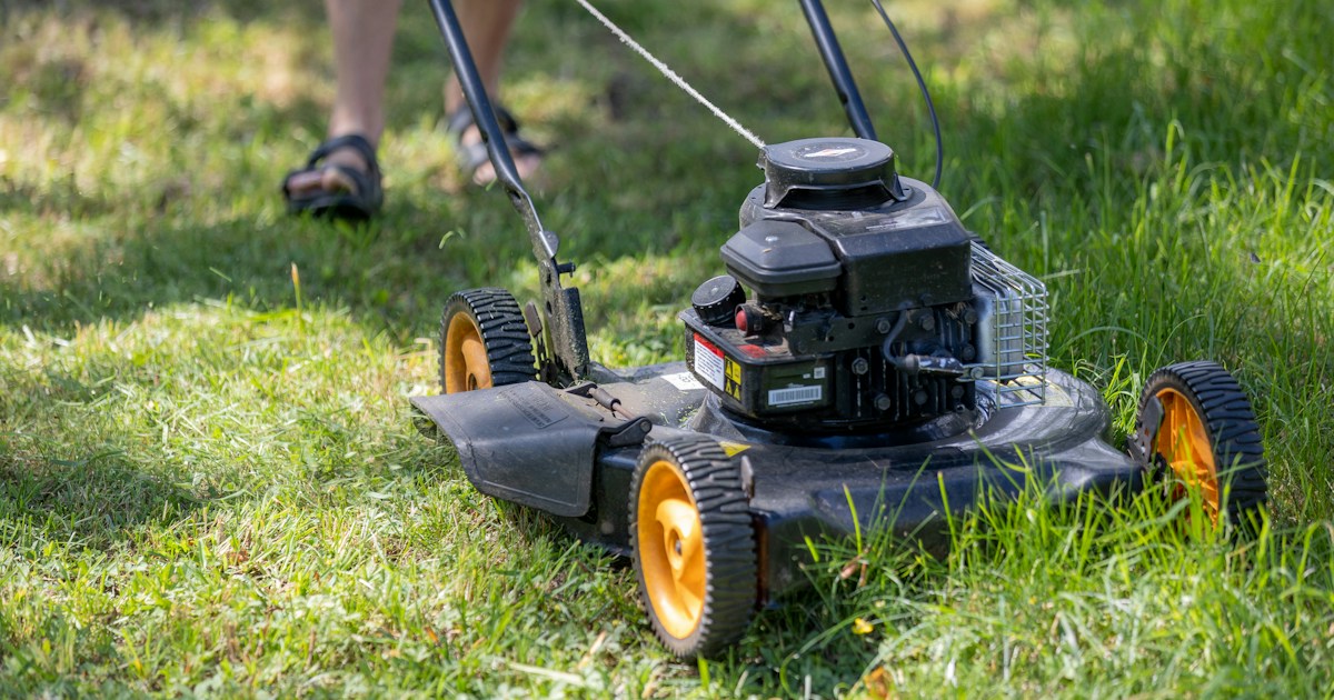 Person operating a lawn mower on green grass