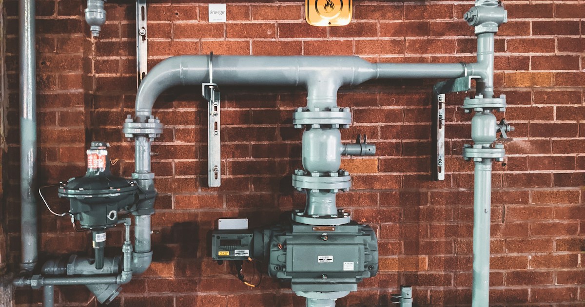 Industrial plumbing pipes and valves on brick wall