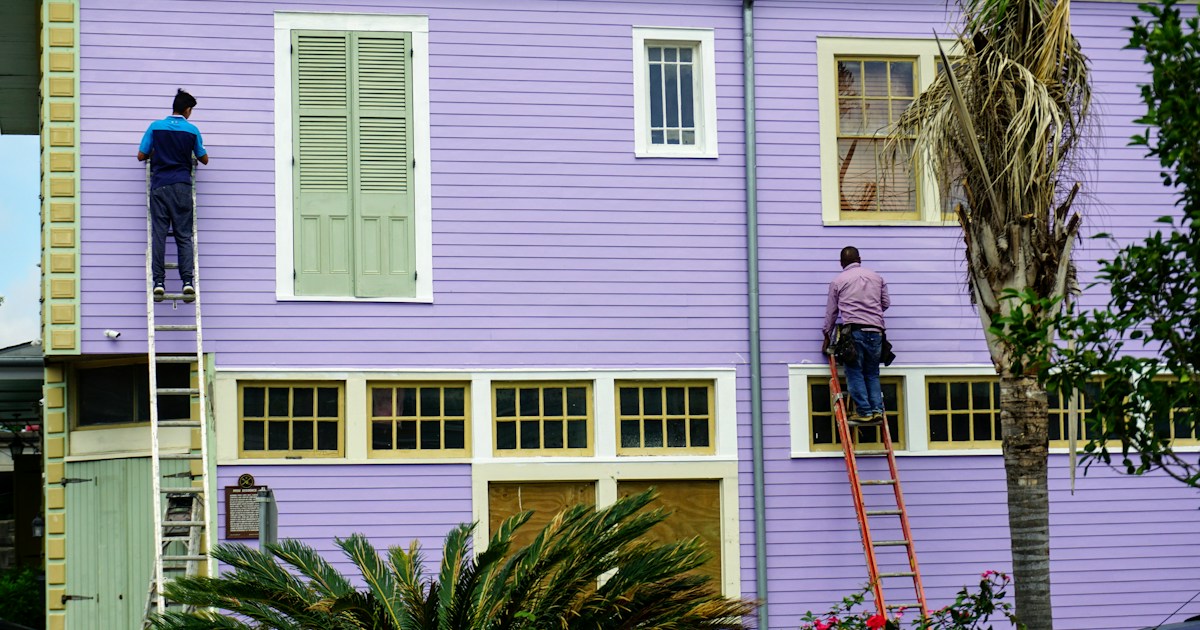 Pintores profesionales en escaleras pintando exterior de casa residencial