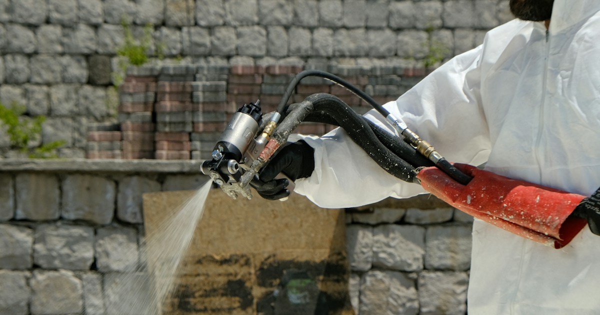 Técnico de control de plagas rociando pesticida con equipo profesional